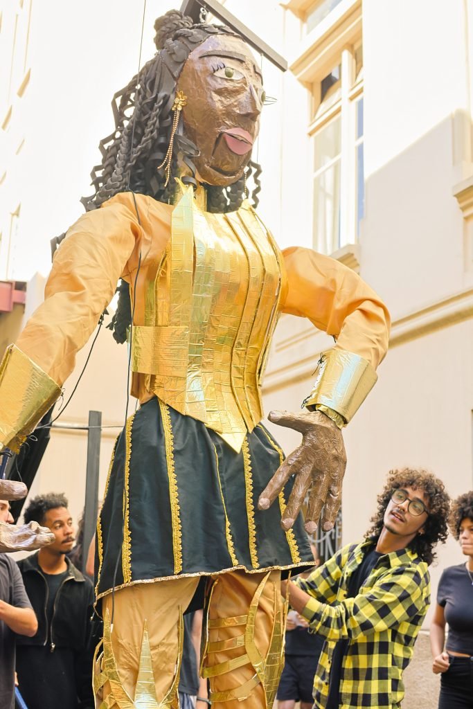 Cortejo pelas ruas do Brás com a boneca gigante feita pelos alunos de Técnicas de Palco, na sede Brás da SP Escola de Teatro. (10/06/2024). | Foto: Clara Silva.